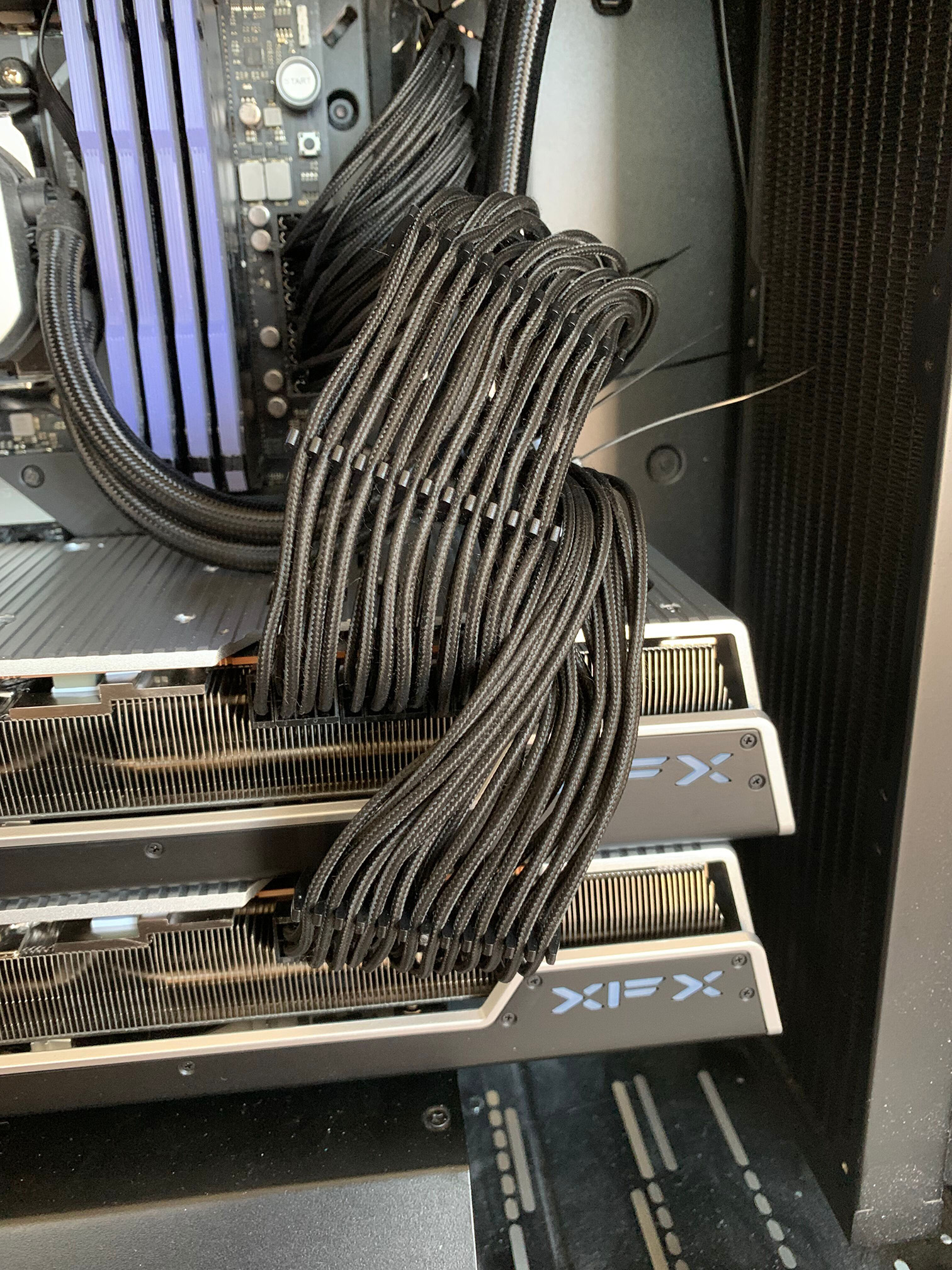 Two XFX AMD Radeon RX 7900XTX GPUs in an open PC case with PCI power cables connected to them